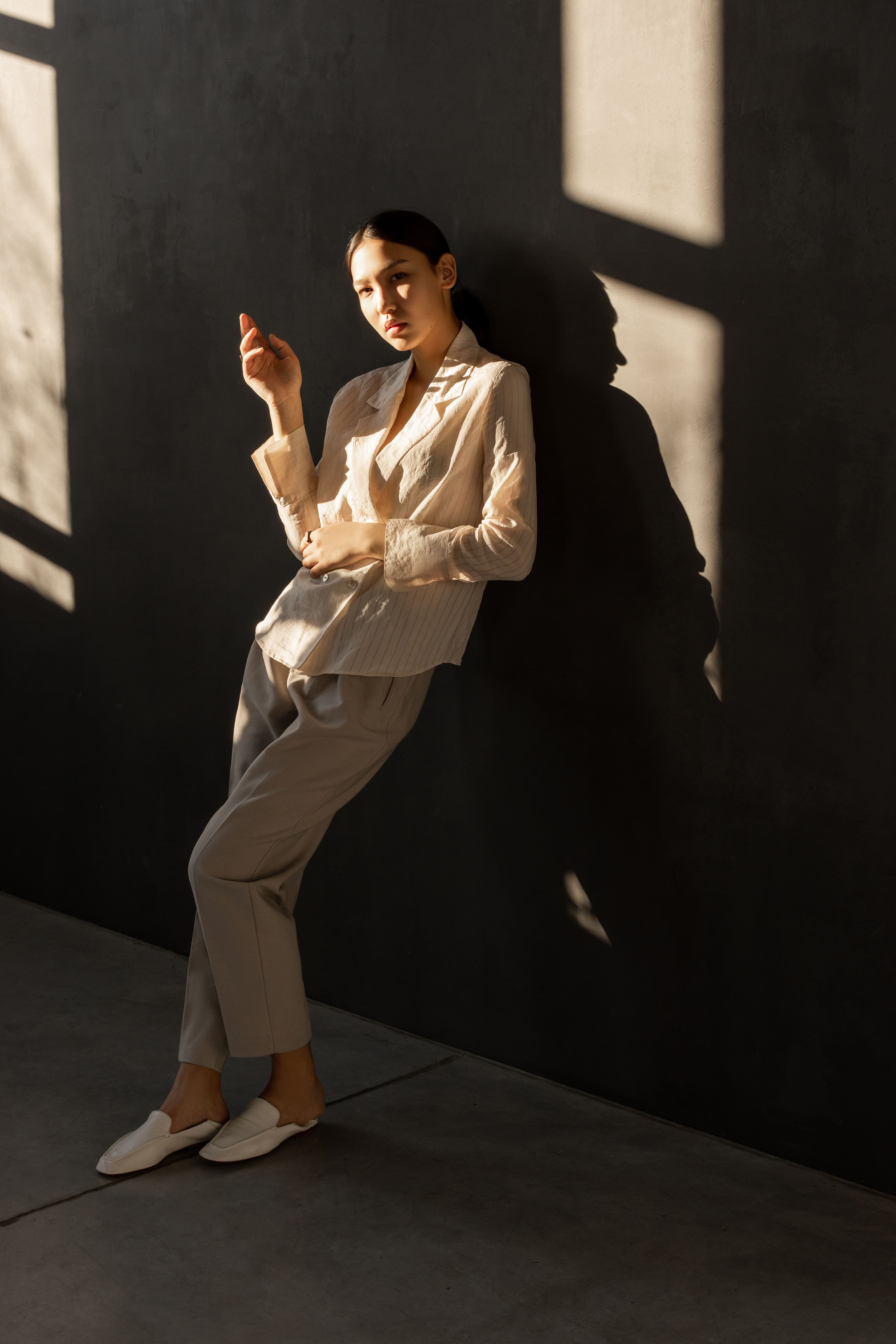 An open wardrobe in morning light, with a full rail of clothes, folded knits on the shelf and shoes on the floor